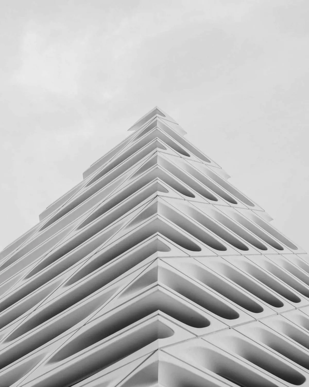 A stepped white building rising into a pale sky, in black and white
